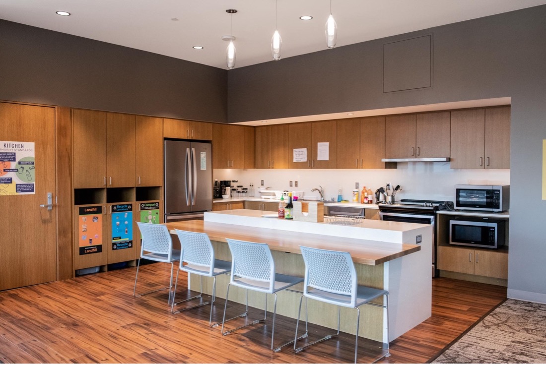 Open kitchen area featuring an island of seating, recycling center, and appliances